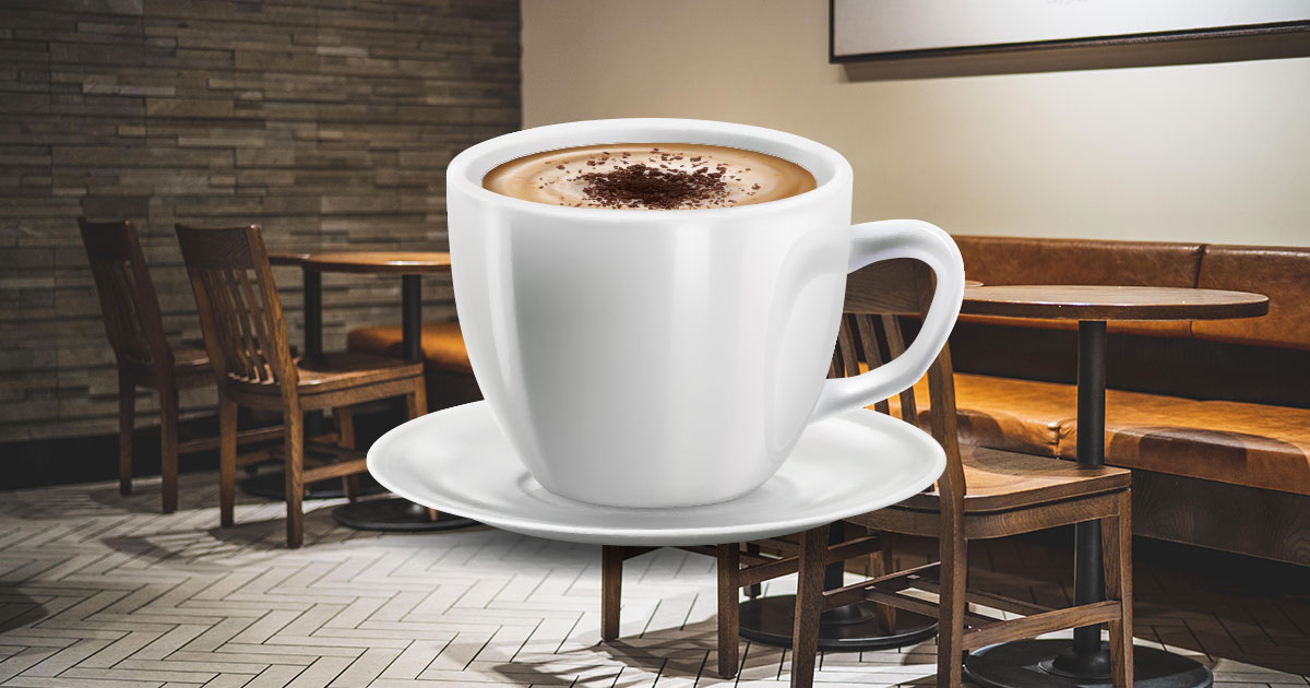 A large cup of coffee in a white mug, with a wooden table in the background
