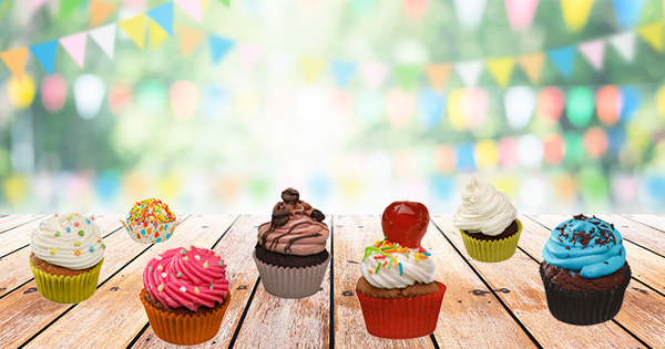 A selection of tempting cupcakes on a table with pastel bunting in the background
